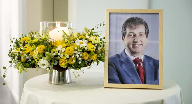 Ein Foto des Bundesratssprechers und Vizekanzlers Andre Simonazzi sowie ein Blumenstrauss und eine Kerze, fotografiert auf einem Tisch, vor den drei Pressekonferenzen des Bundesrates, am Mittwoch, 15. Mai 2024, im Medienzentrum Bundeshaus in Bern. Der lan
